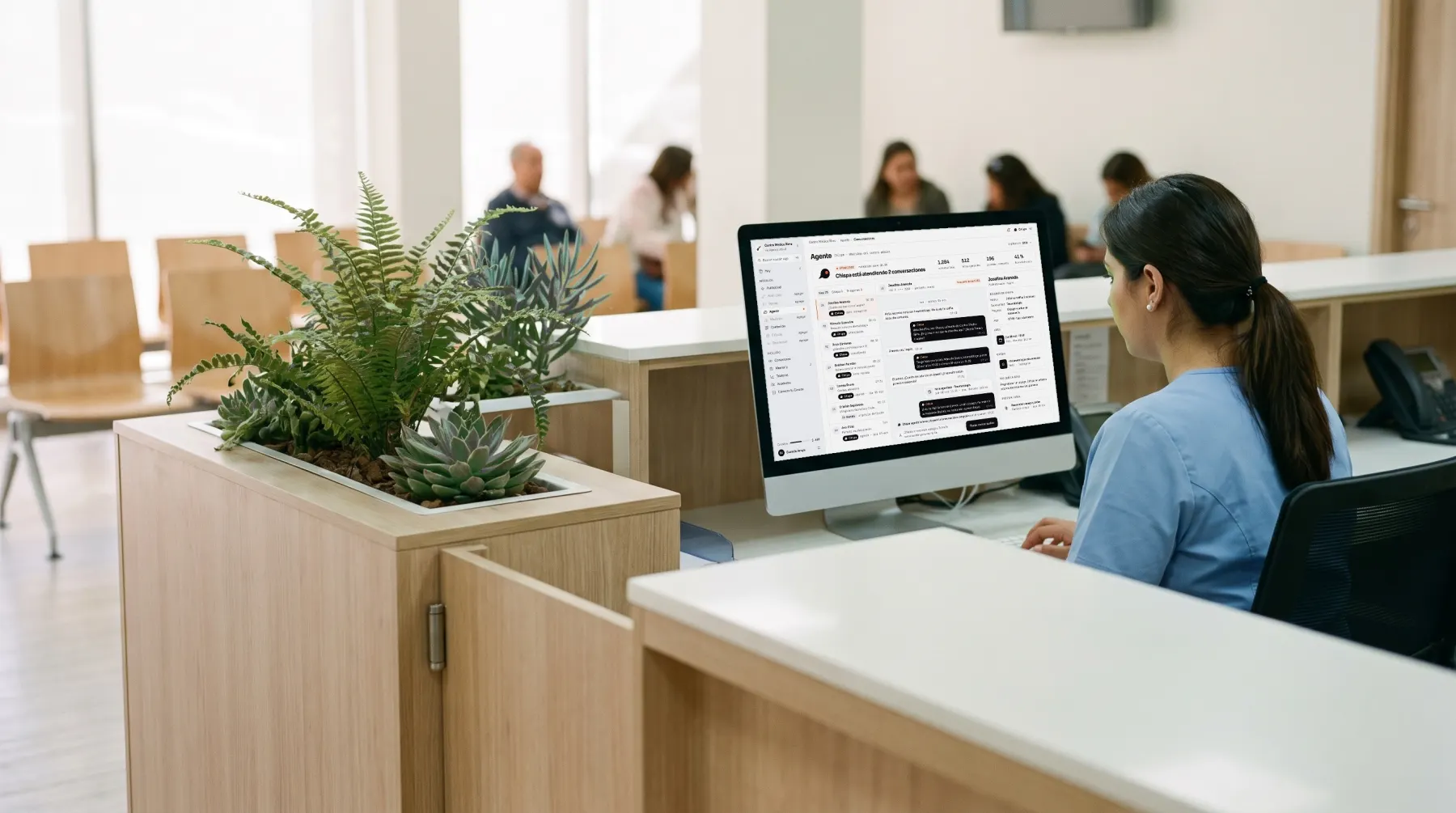 Recepción de un centro médico; en el monitor, la bandeja de conversaciones que atiende Chispa.