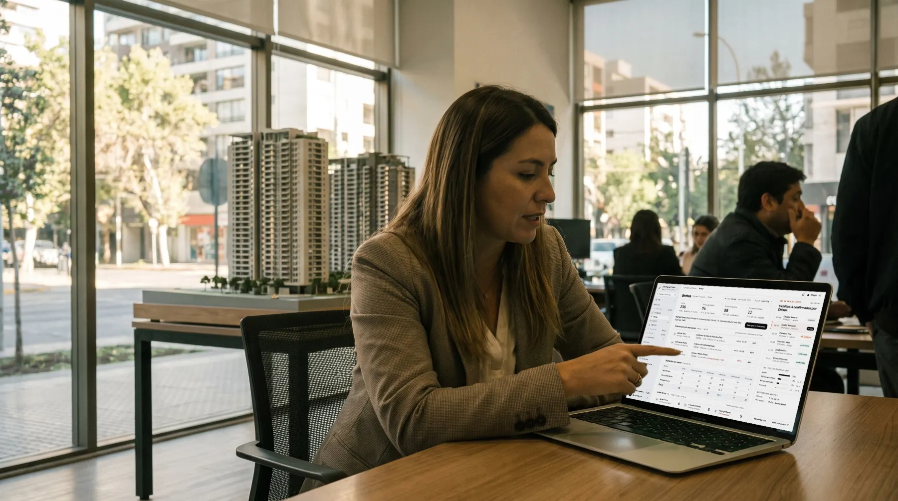 Andrea Morales, jefa de ventas, señala en su notebook la próxima tarea de cada asesor, en la sala de ventas con la maqueta del proyecto.